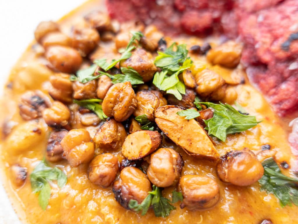 Close up of vegan African peanut soup with crispy chickpeas and roasted almonds. 