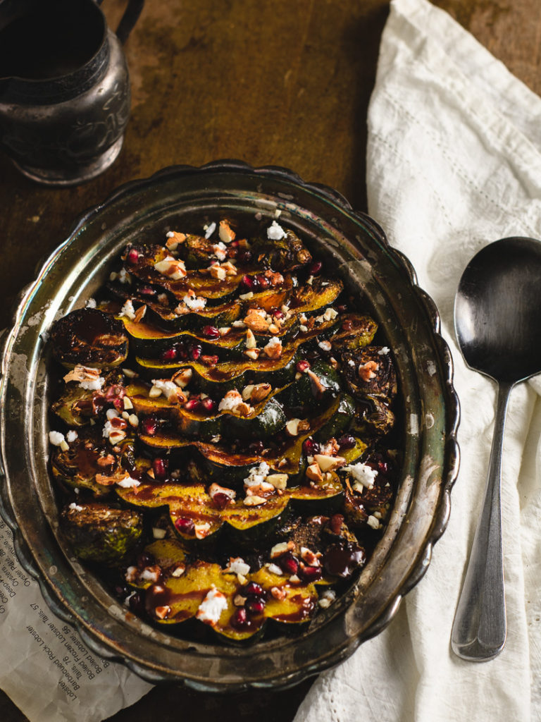 Side dish of roasted brussel sprouts and delicata squash set on the table.