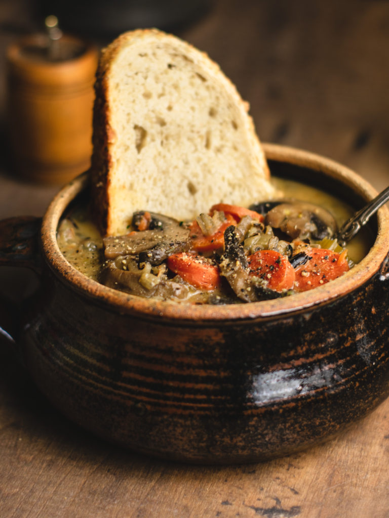 Close up shot of wild rice soup and a slice of bread